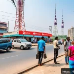 Home 22 나이지리아에서 인터넷 사용하기 - A vibrant urban street scene in Lagos, Nigeria, showcasing people using smartphones and laptops outd...
